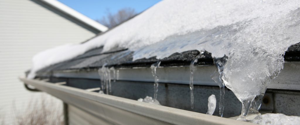 Gutter and roof edge covered in ice and snow after a winter storm