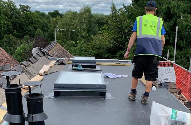 Roofer working on a commercial flat roof with rooflights